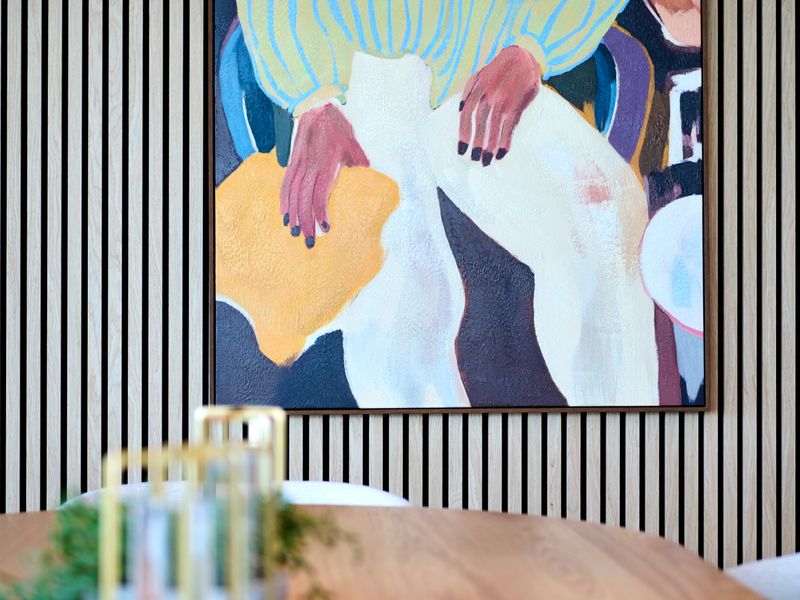 Colorful abstract wall art set against a textured slatted wall.
