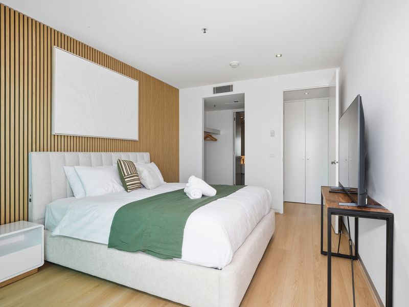 Comfortable queen bedroom with neutral tones and clean white linens.