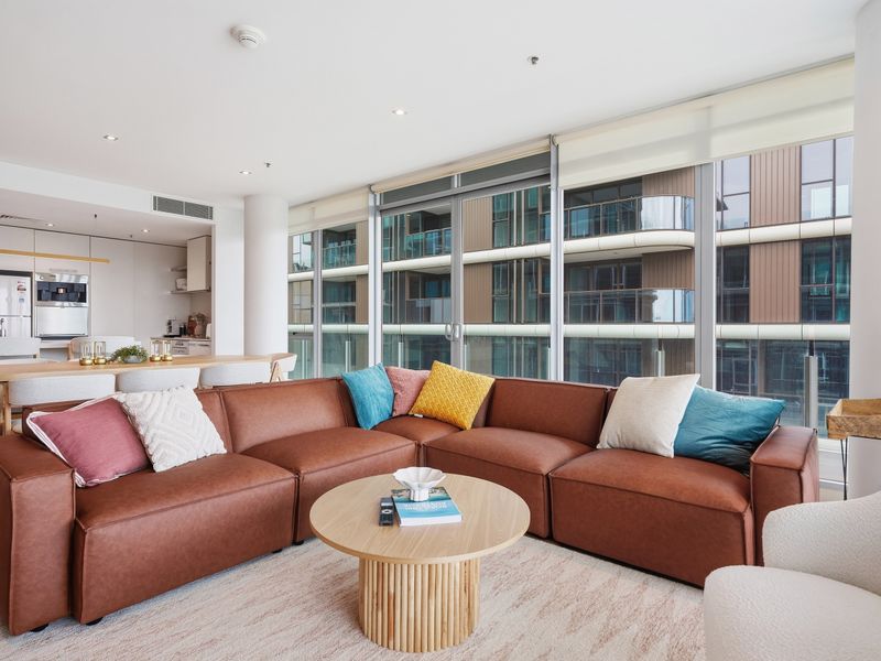 Bright living space featuring a large wrap-around brown leather sofa and coffee table.