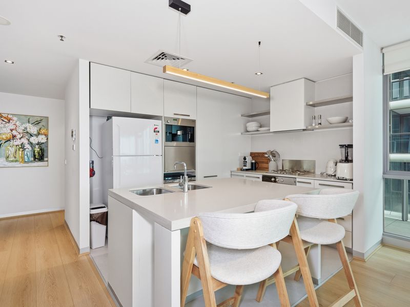 Modern kitchen and dining space with white counters, an island, and bar stools.