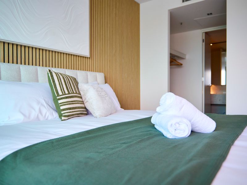 Master bedroom showcasing a green accent throw blanket and soft lighting.