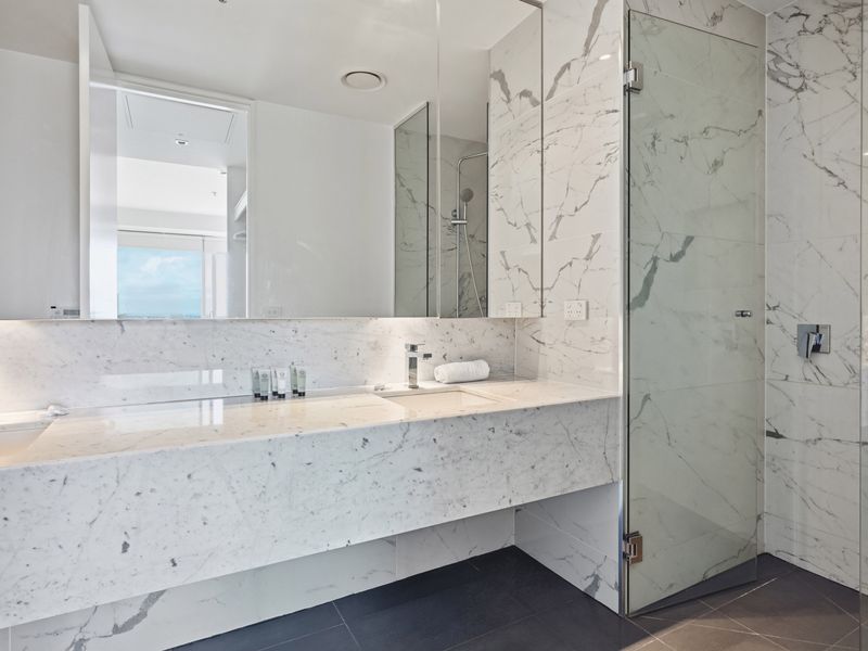 Marble-tiled bathroom counter with a sleek sink and mirror.