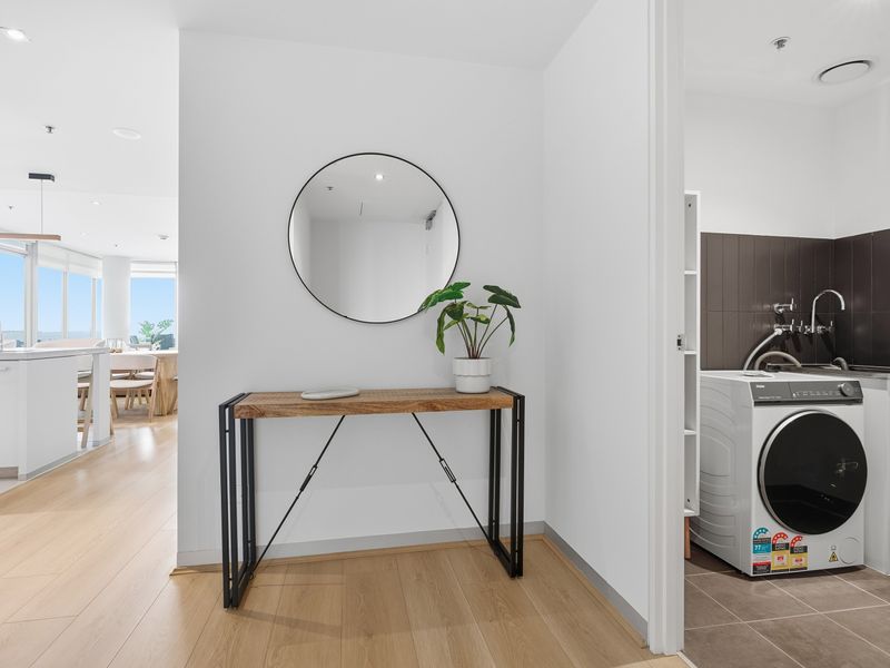 Minimalist entryway console table with a round mirror and plant.
