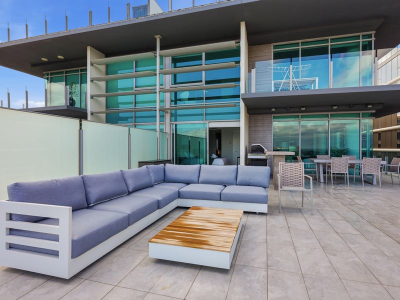 Large outdoor sectional sofa setup on the paved rooftop deck.