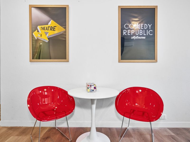 Small dining nook with a white table and two vibrant red chairs.