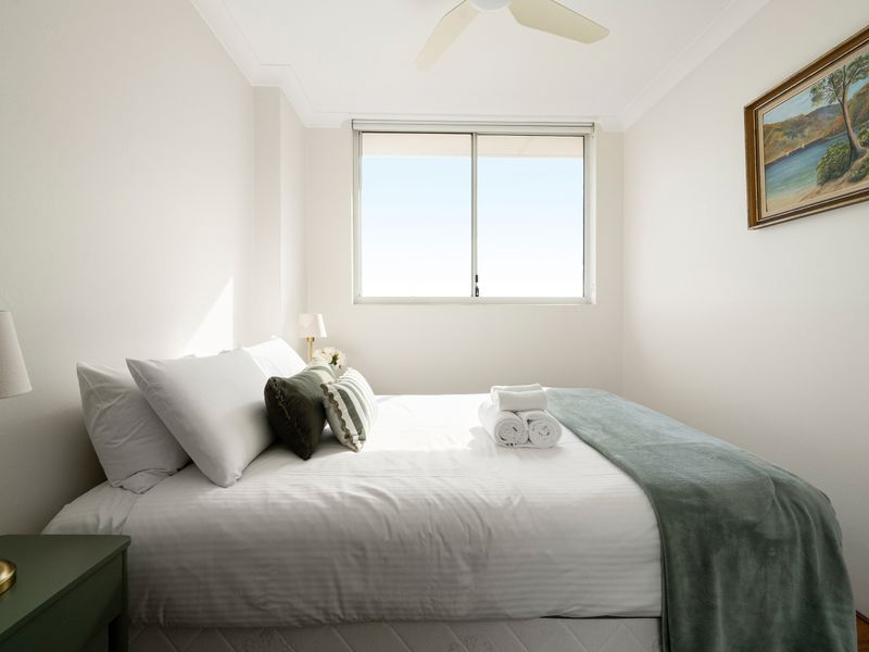 : Featuring a beautifully dressed bed with plush pillows and a soft, sage-green accent throw.