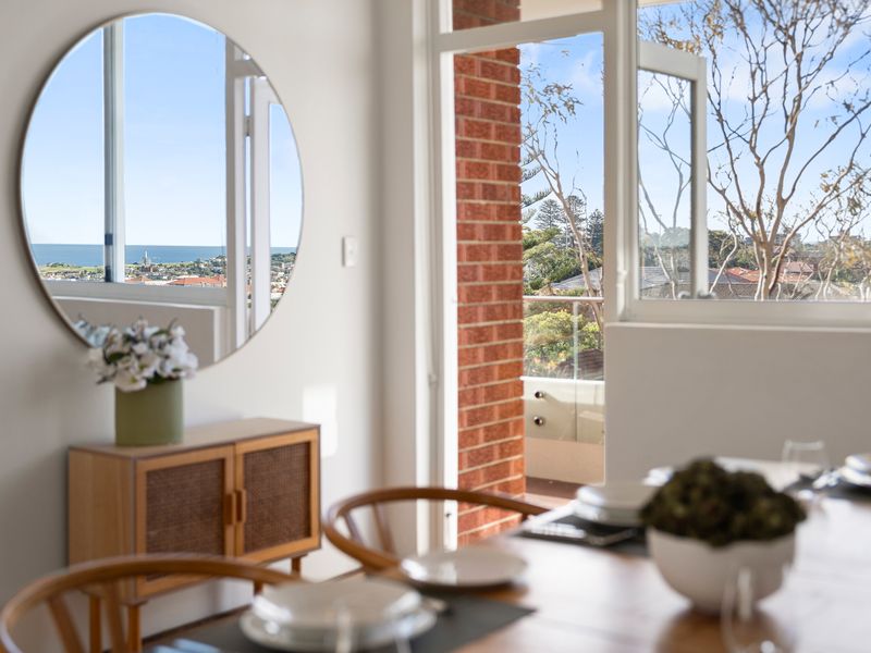 Bright modern dining space opening onto a balcony with scenic coastal views.