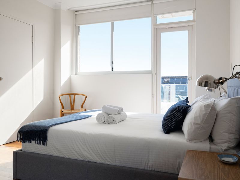 Bright, minimalist bedroom filled with morning light and a balcony view.