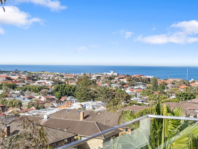 Elevated viewpoint overlooking a coastal town and the sea under a blue sky.