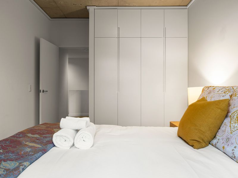 Modern bedroom featuring a neatly made bed and crisp white linens.
