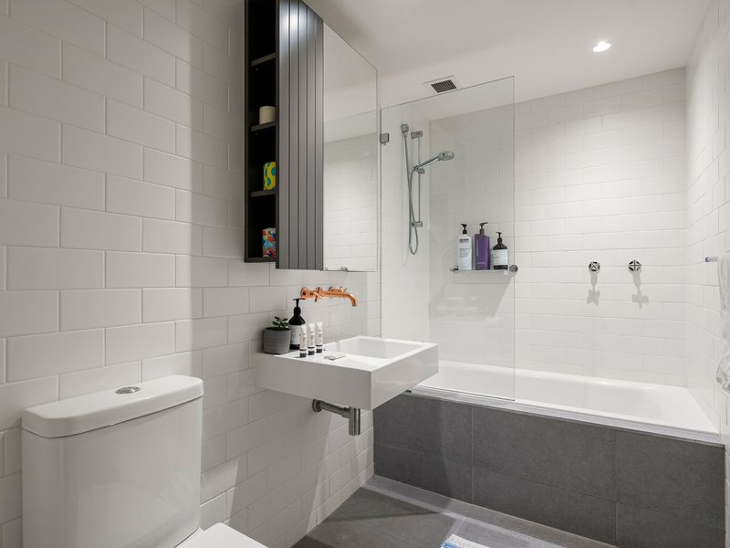 Contemporary bathroom equipped with a white vanity sink, toilet, and combined shower-bathtub.