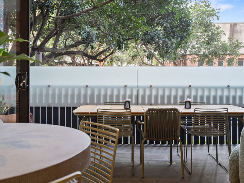 Outdoor patio dining setting surrounded by trees and lush property landscaping.