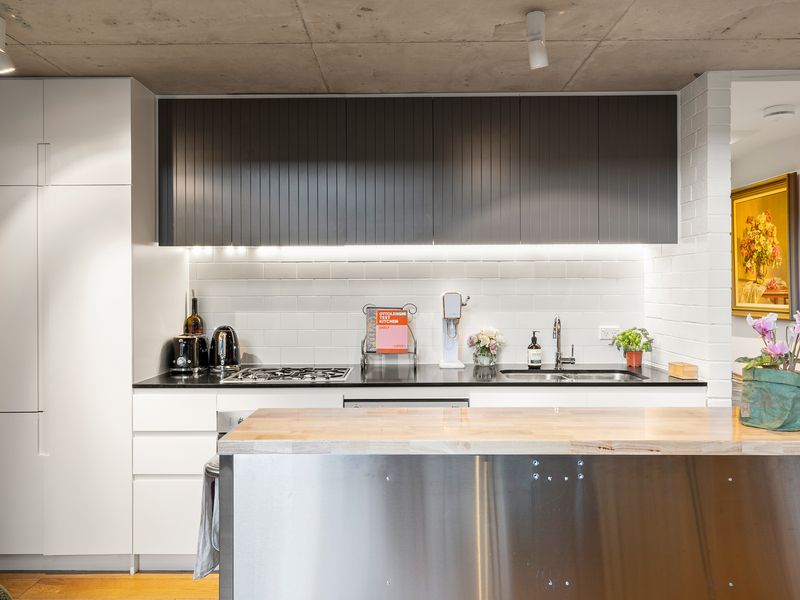 Sleek modern kitchen showcasing clean white countertops, upper cabinetry, and high-end stainless steel fixtures.