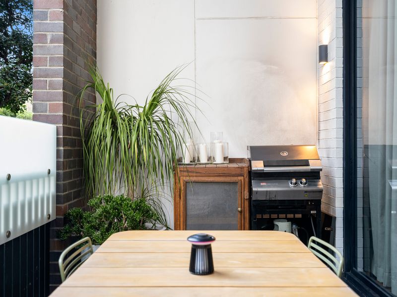 Private outdoor terrace equipped with a dining table and surrounded by lush green foliage.