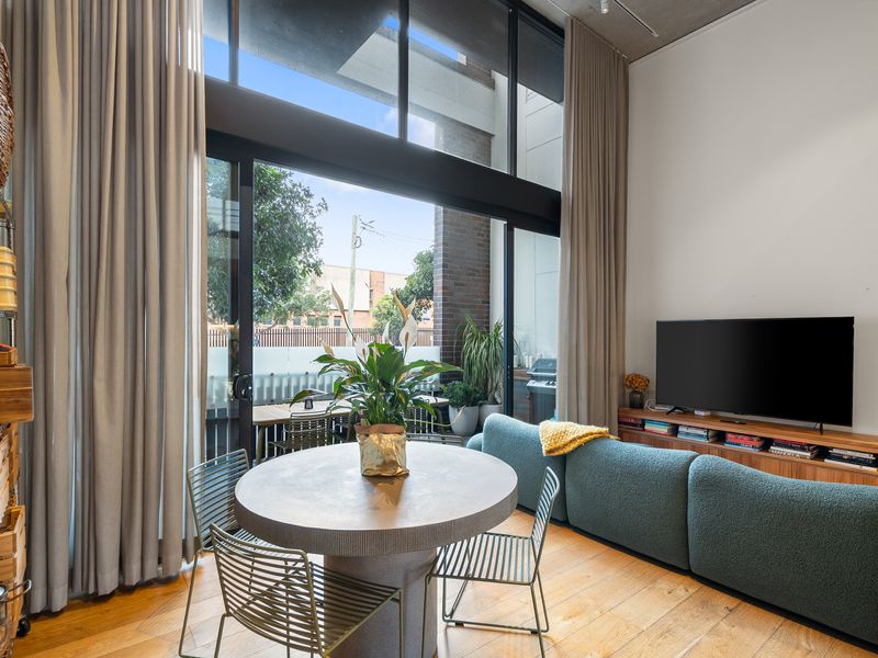 Alternative view of the living and dining zone highlighting the modern track lighting and flat-screen television setup.