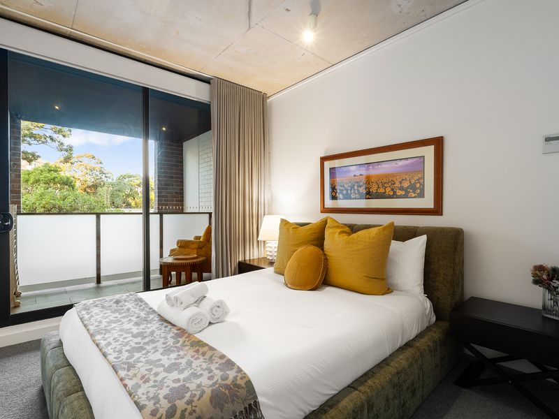 Cozy bedroom view with soft lighting, a bedside table, and decorative wall art.