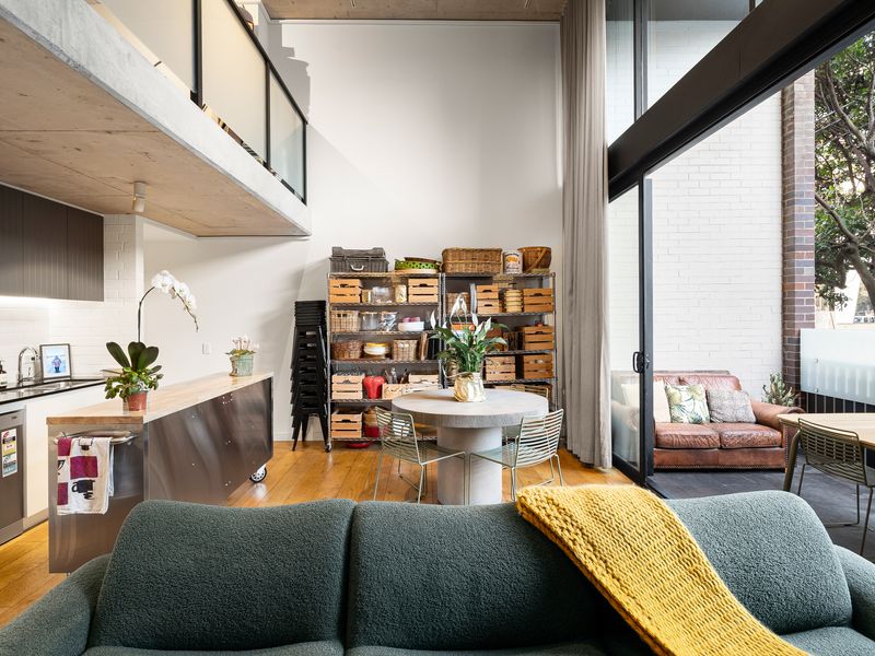 Spacious double-height living area featuring soaring ceilings, expansive glass windows, and a comfortable seating arrangement.