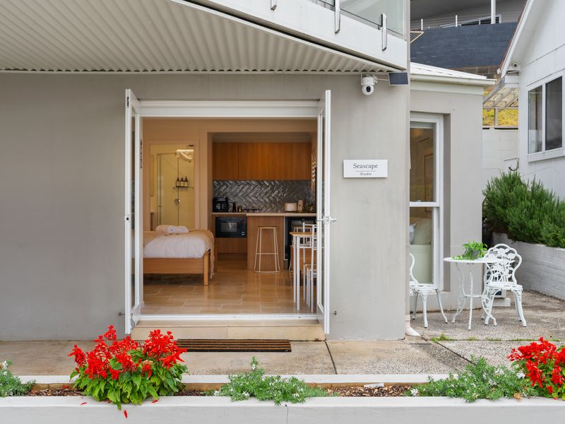 Exterior ground-floor view of the property entrance with potted plants and outdoor seating.