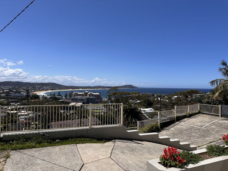 Elevated coastal vantage point capturing panoramic views of the ocean, sandy beach, and surrounding township from an open terrace.