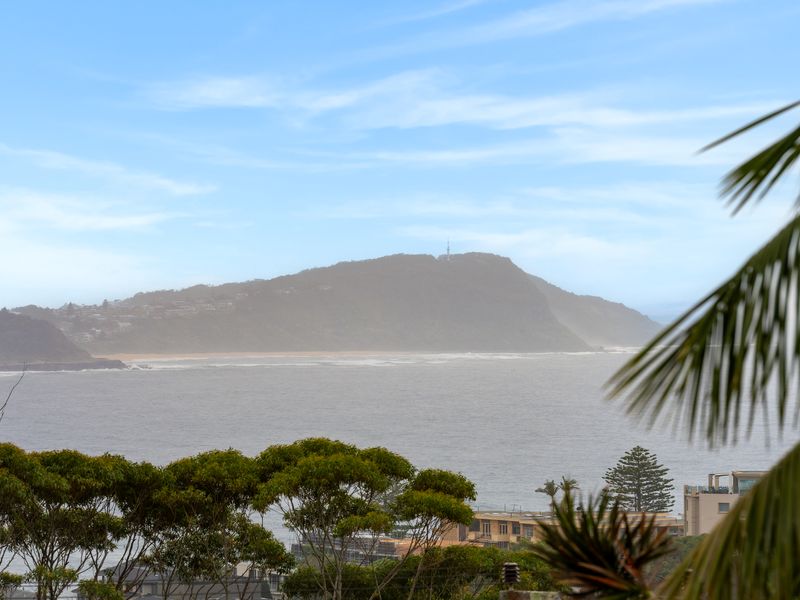 Scenic coastal outlook showcasing distant mountains, hillside homes, and the waterfront.