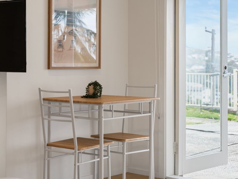 Compact indoor dining set positioned by a bright window and sliding glass door.