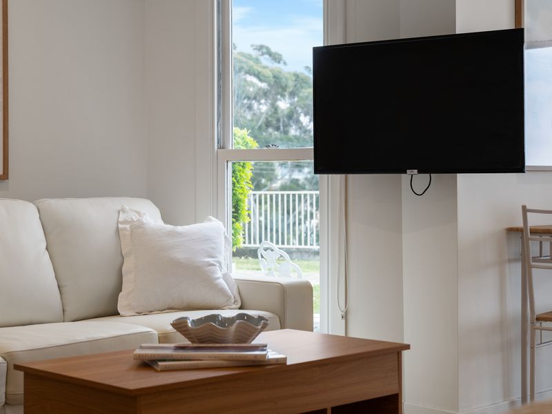 Living room lounge featuring a neutral sofa and a wall-mounted television.