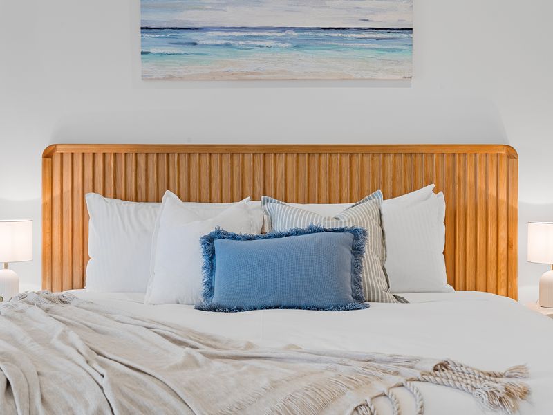 Comfortable bedroom featuring a wooden headboard, crisp white linens, and a blue accent pillow.
