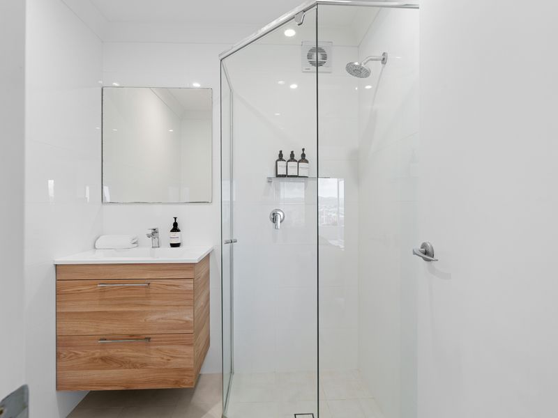 Modern bathroom equipped with a glass-enclosed shower, wooden vanity, and sleek fixtures.