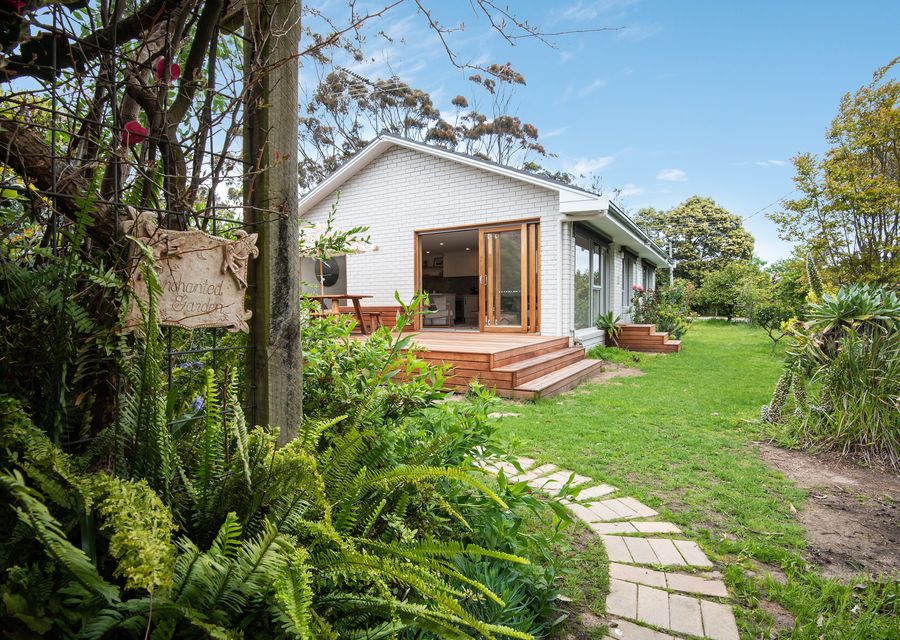 Lush greenery and trees surrounds the house.