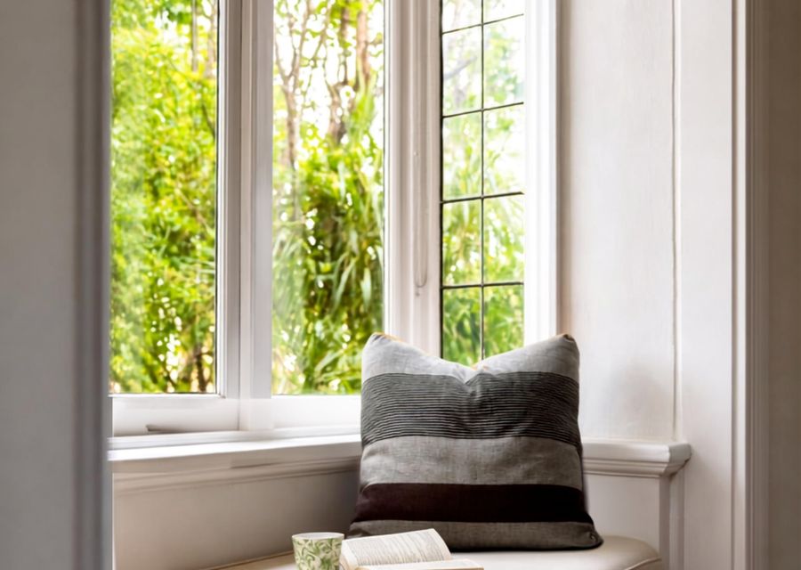 Bright bedroom with built-in shelving and leafy garden outlook