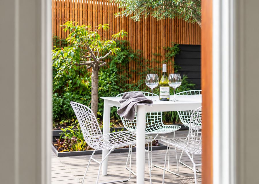 Private outdoor dining area surrounded by established greenery