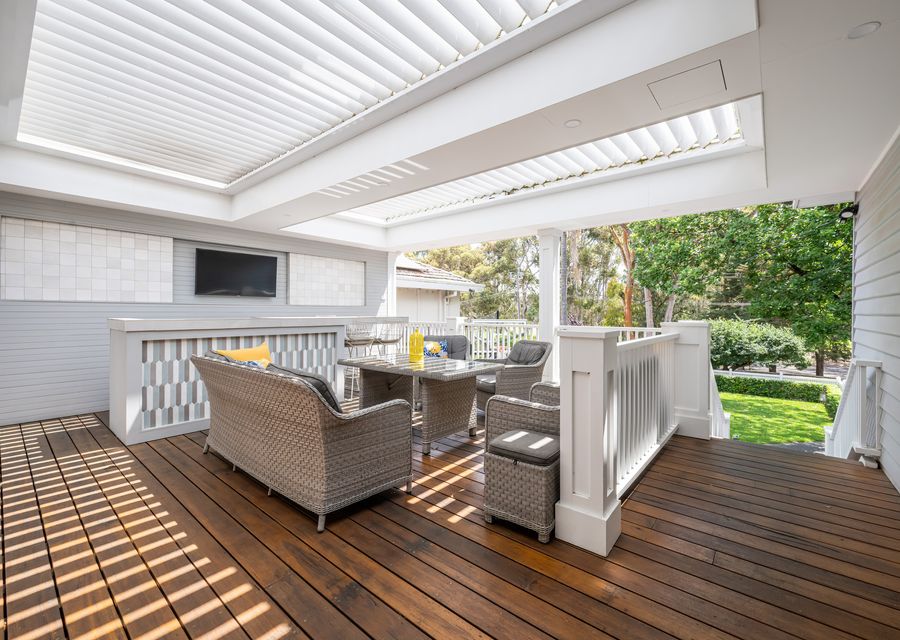 Spacious all-weather outdoor deck featuring comfortable lounge seating and a large dining table—perfect for alfresco meals.