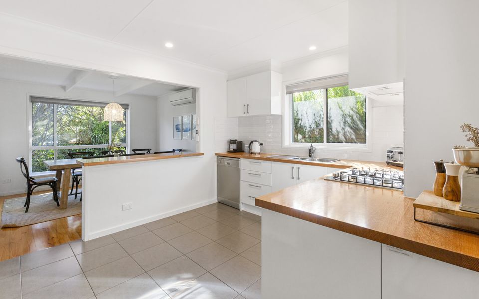 Open plan kitchen with breakfast bar and four stools.