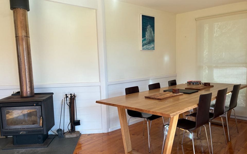 Dining table with seating for six, set beside a wood fire for cosy winter feasts.