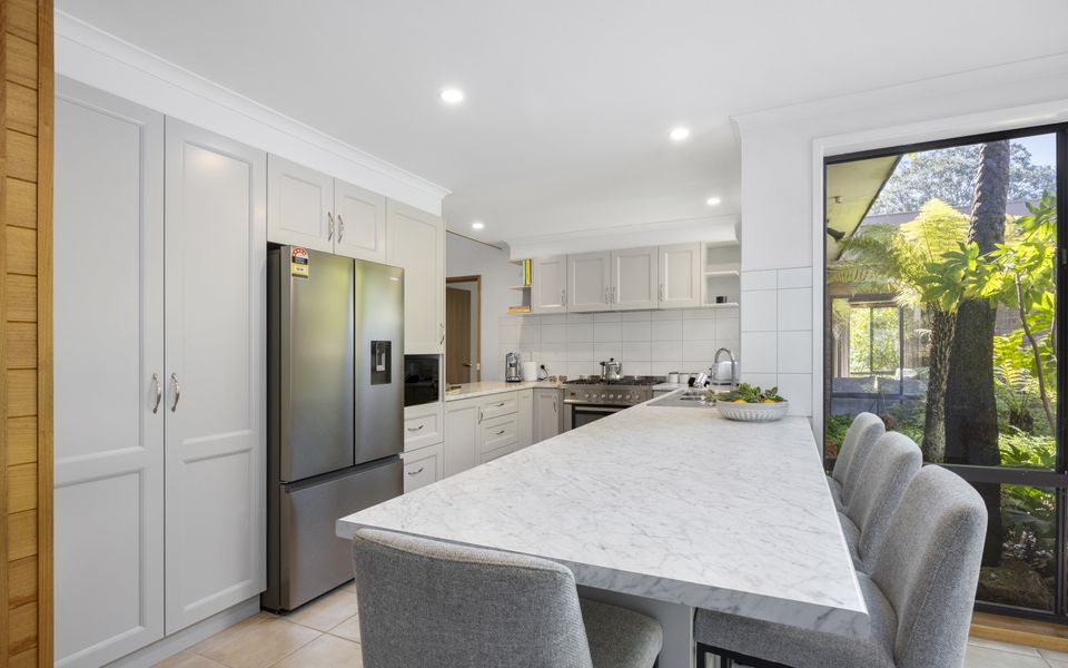 Spacious kitchen featuring modern appliances and a breakfast bench with stools