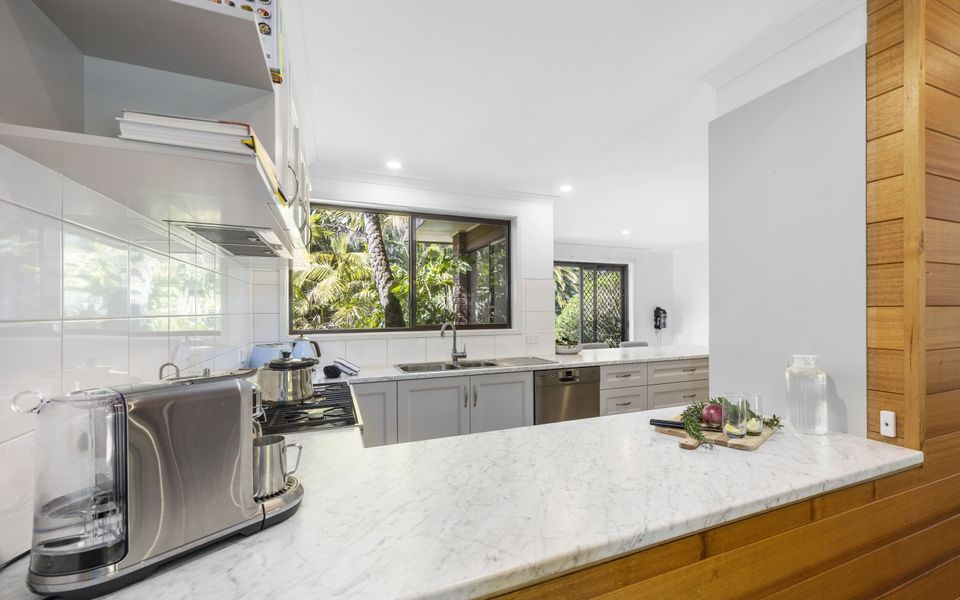 Spacious kitchen featuring modern appliances and a breakfast bench with stools
