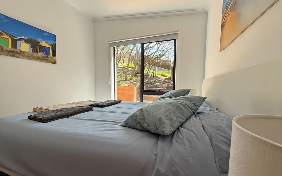 Bedroom two features a queen bed and views of the back garden