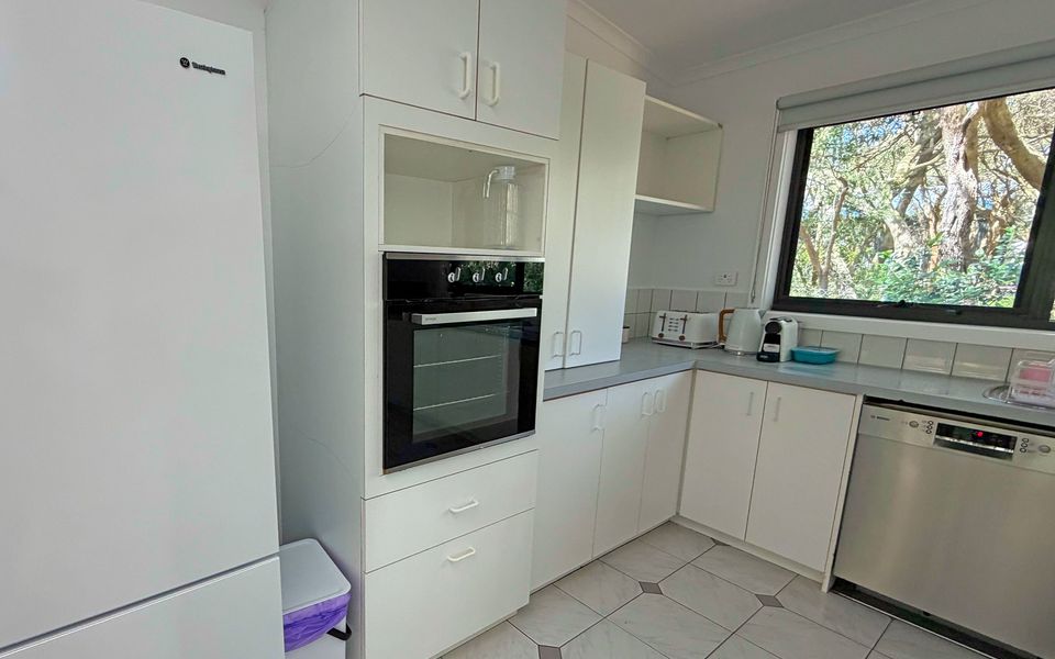 Light, spacious kitchen with coffee machine, gas cooktop, microwave, dishwasher, oven and a breakfast bench with stools.