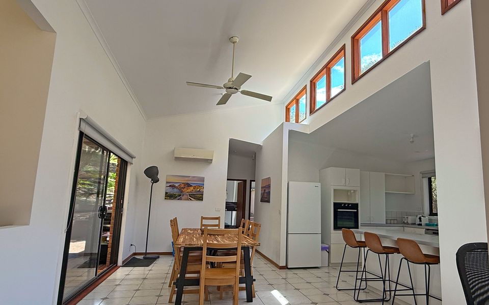 Bright and spacious kitchen and dining space with split-system comfort, breakfast bench seating, and sliding doors to the outdoor entertaining area.