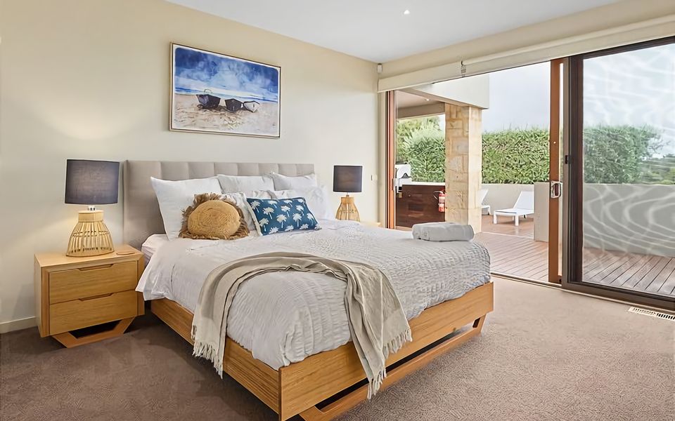 Experience ultimate comfort in the king bed of this stylishly furnished bedroom with access to back deck.