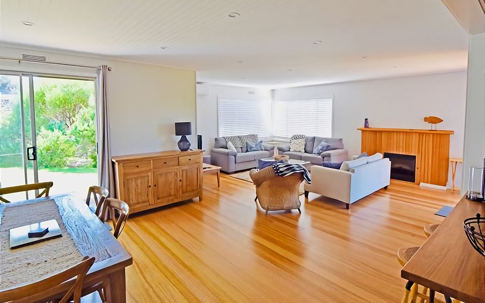 Open plan living that takes you out onto the back deck through sliding doors, looking over the green lawn and native trees that surround the property.