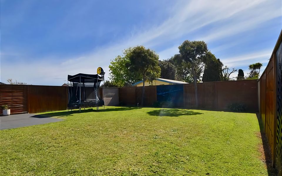 Trampoline with basketball hoop within very private, fully fenced backyard.