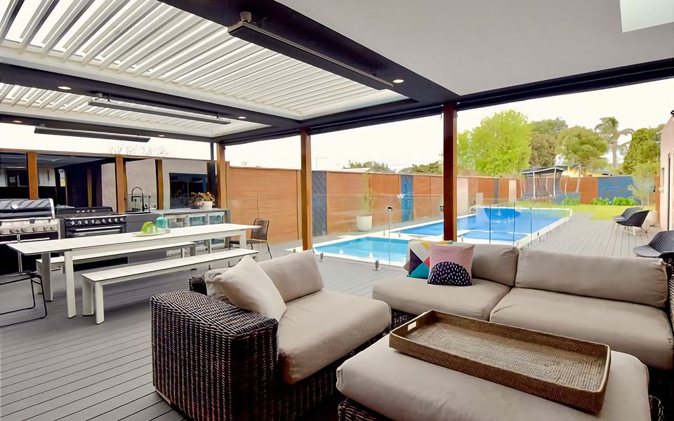 An expansive alfresco dining area thoughtfully designed for entertaining, featuring an outdoor kitchen, cozy lounging spaces, and dining table.