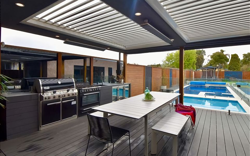 Outdoor Kitchen with Weber BBQ, 5-burner stove and large gas oven, food prep area with deep sink, and bar fridges.