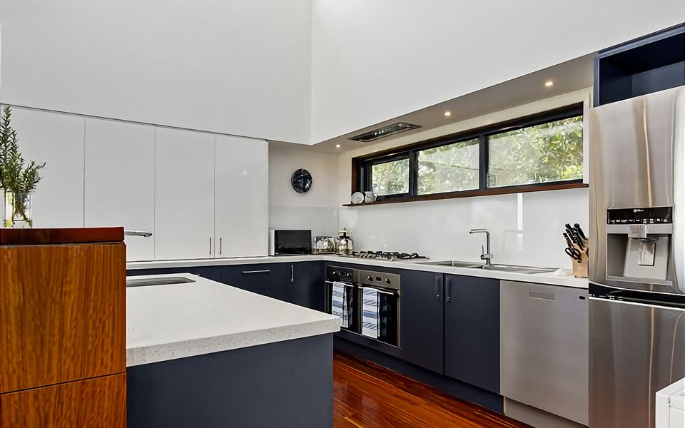 Open-plan kitchen is fully equipped with tall breakfast bench and high-quality appliances.