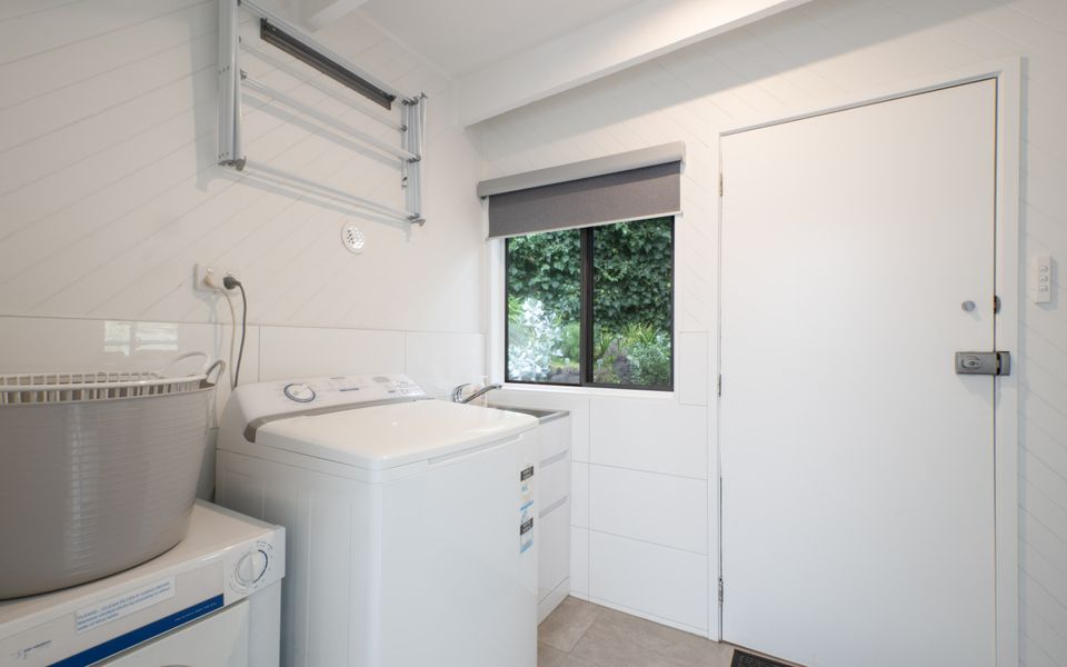 Laundry with dryer and washing machine and access to the back patio and terraced gardens