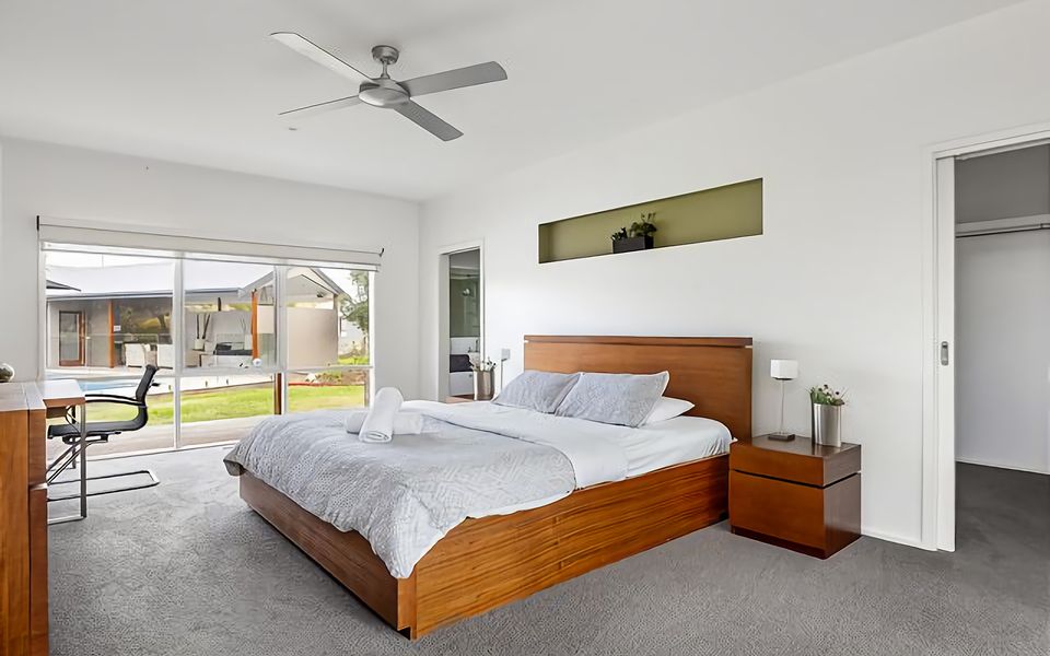 Master Suite: King Bed with ensuite, ceiling fan, air conditioning, small TV, desk, walk-in-robe, and pool views.