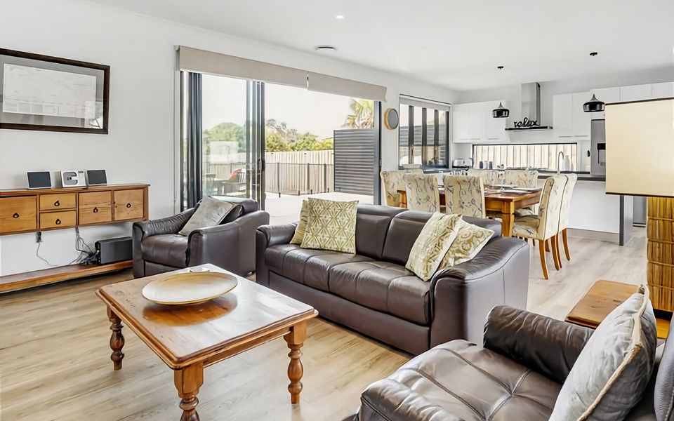 Living area with a comfy couch and relaxing lounge chairs along with large TV.