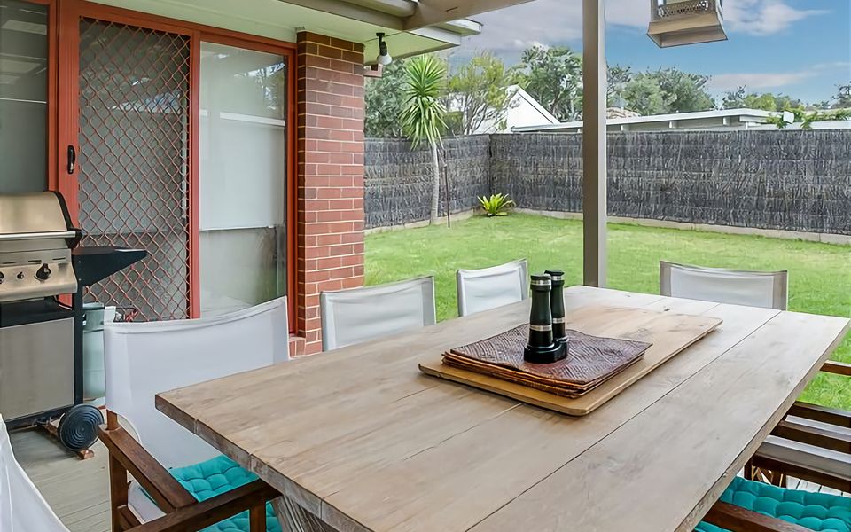 Large deck with an outdoor setting for eight and a BBQ overlooking the beautifully maintained lawn area.