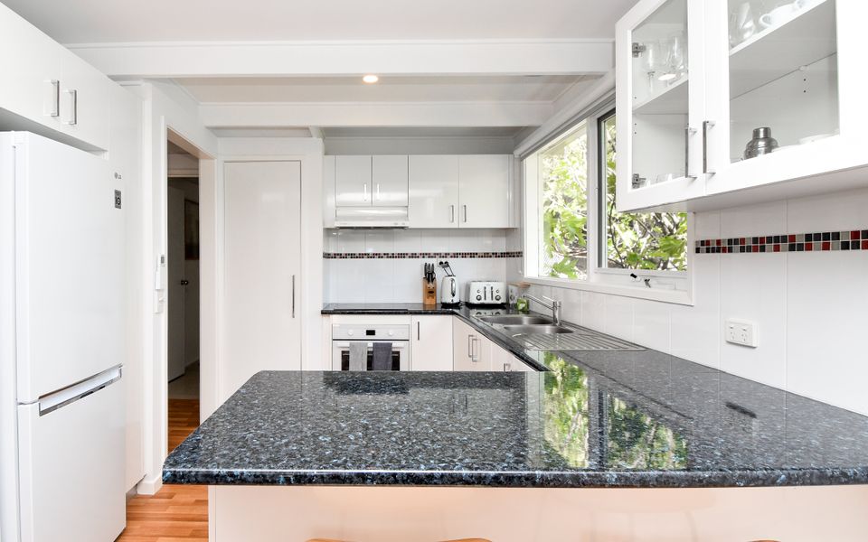 Fully equipped kitchen with a breakfast bench with 2 stools.